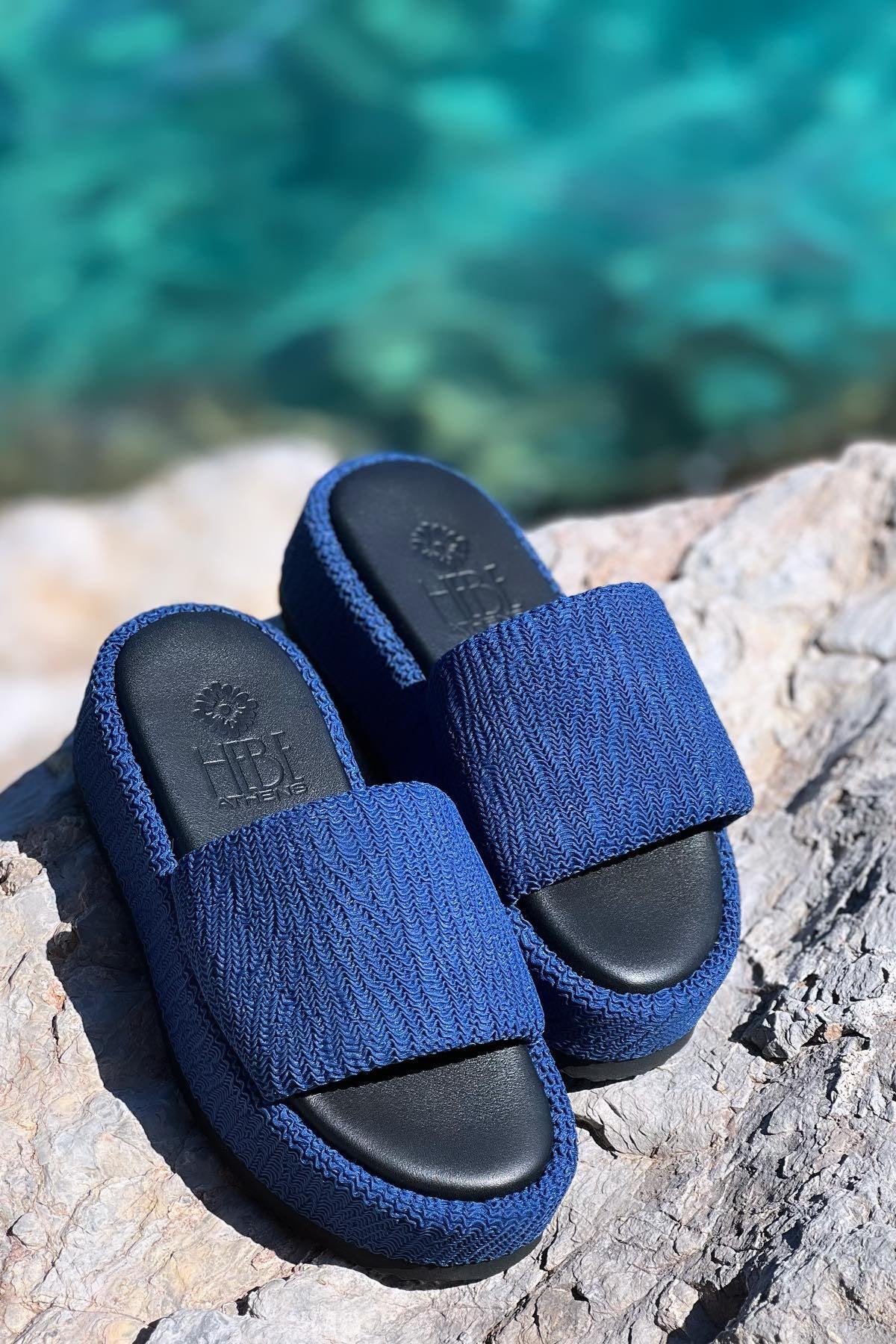 Pair of blue platform slides on rocks near water