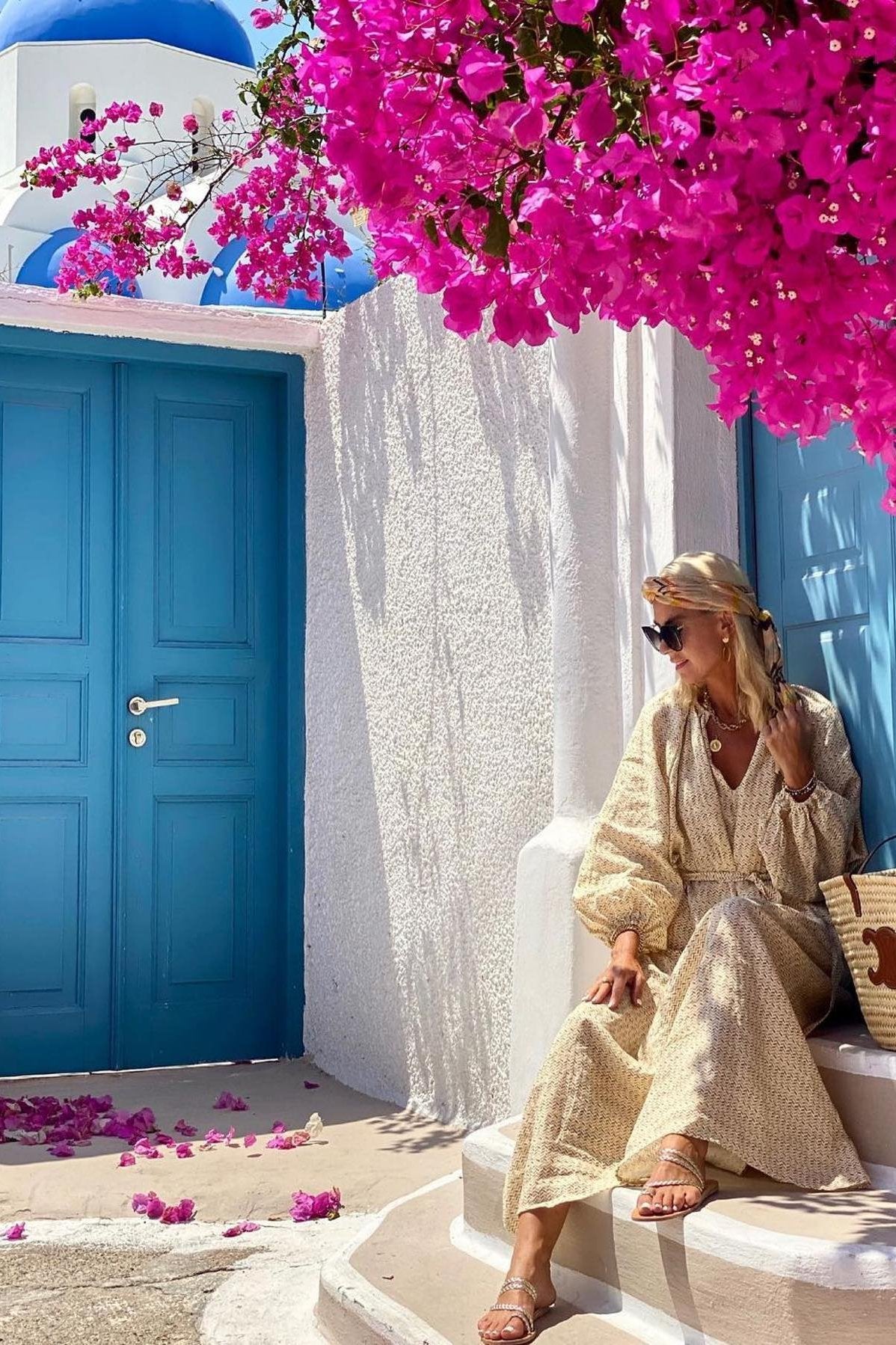 Model wearing gold sandals under a pink bougainvillea