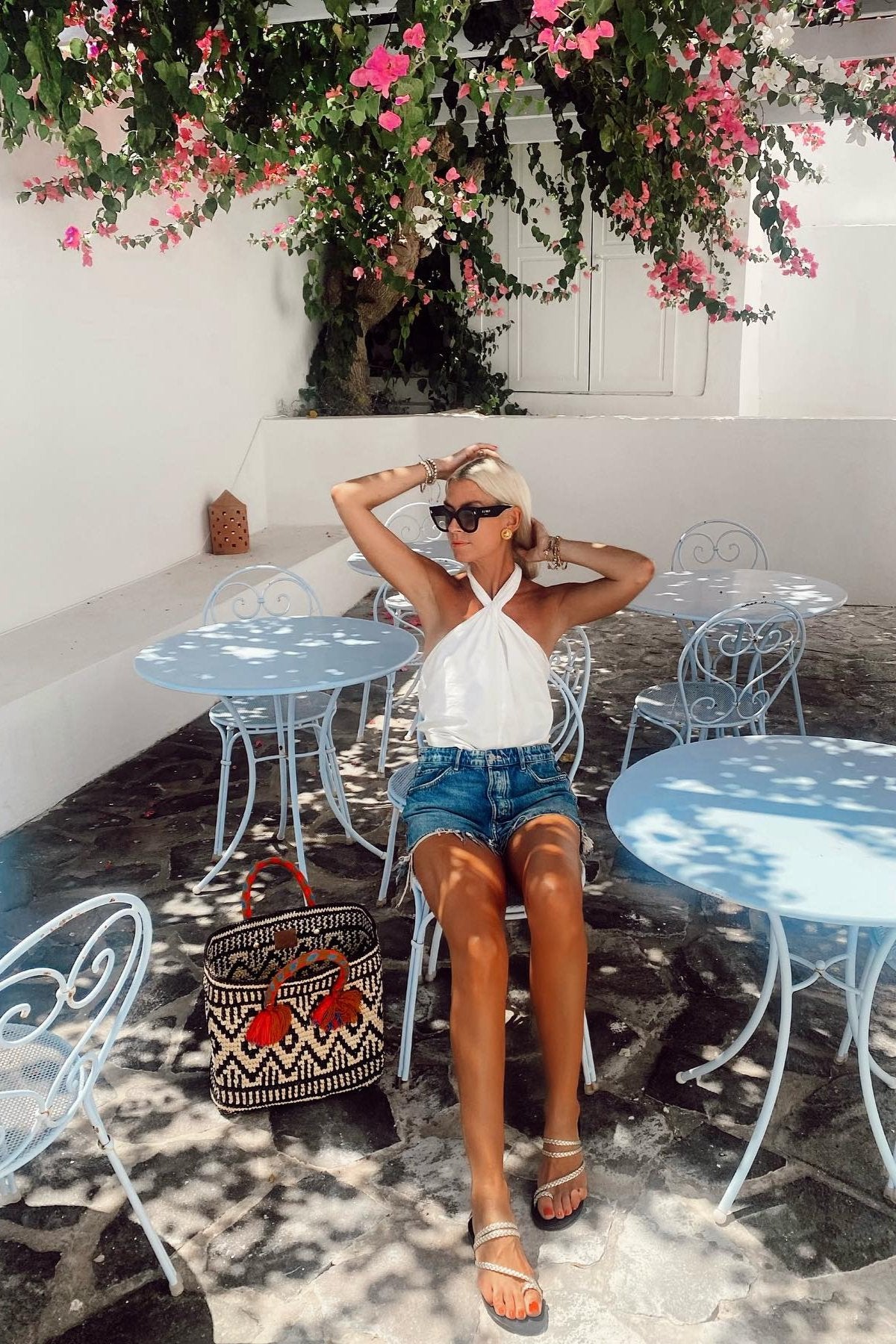 Model sitting down wearing white top jeans and gold sandals